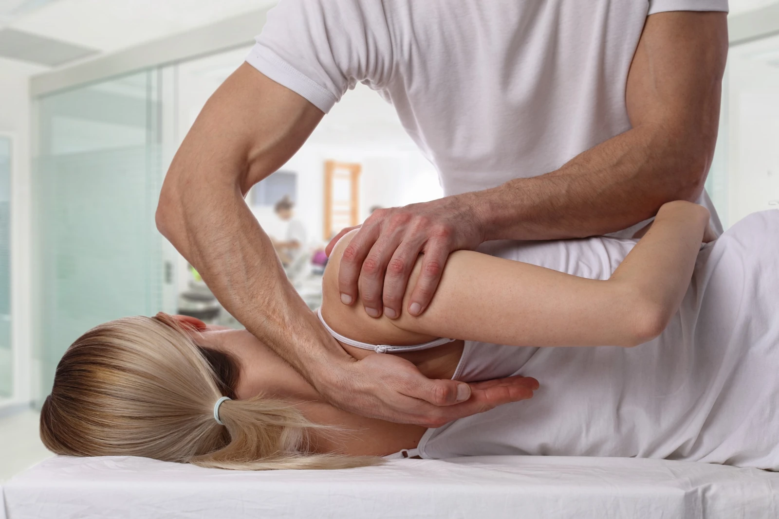 Hands applying pressure to a person’s lower back on a treatment table.